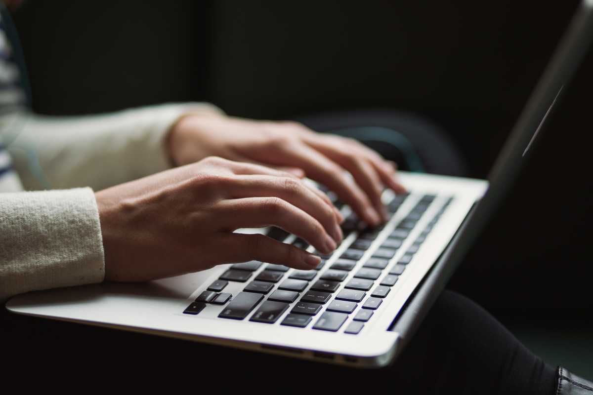  A person is typing 'RUU Keamanan Siber 2024 Malaysia' on a laptop keyboard.